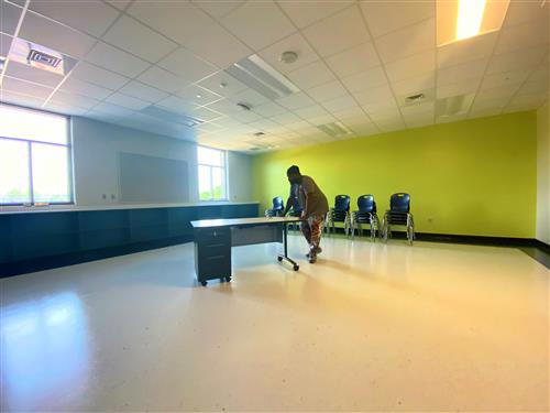 workman rolling desk in place in classroom